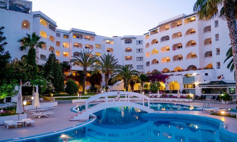 Vue panoramique de la piscine extérieure entourée de chaises longues au Sol Azur Beach Congrès