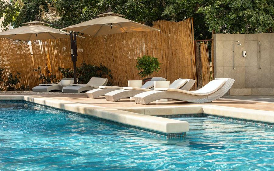 Piscine entourée de chaises longues et de parasols à Golden Tulip Mechtel